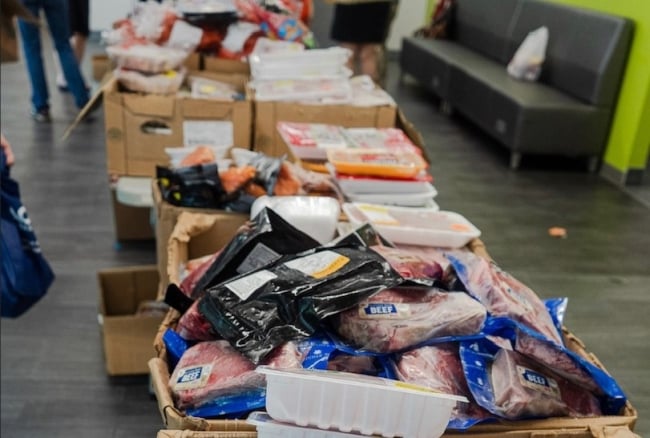 Pace University's mobile food pantry displays a variety of free food items, including plastic-wrapped cuts of meat.